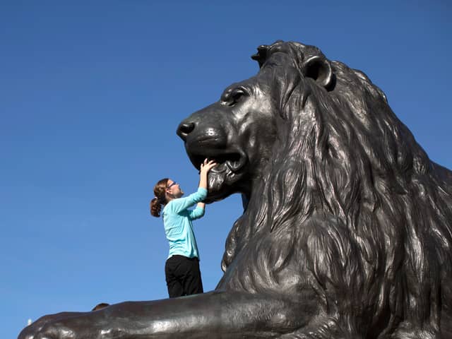 A girl climbs on one of the statues of a Lion in Trafalgar Square
