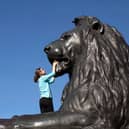 A girl climbs on one of the statues of a Lion in Trafalgar Square