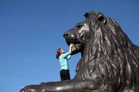 A girl climbs on one of the statues of a Lion in Trafalgar Square