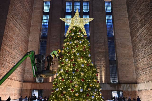 A worker on a cherry-picker makes adjustments to a giant Christmas tree outside Battersea Power Station in south London