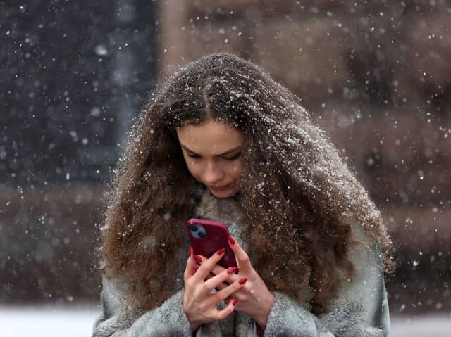 Woman on a smartphone in a snowstorm. Photo: ANATOLII STEPANOV/AFP via Getty Images
