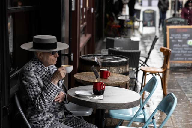 A man drinks a coffee at a cafe in Soho