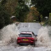 Car drives along flooded road.