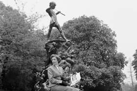 A woman sits beneath the statue of Peter Pan in Kensington Gardens 
