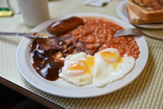 A full English breakfast with eggs, baked beans, bacon, sausage and gravy sauce is served on a table at Regency Cafe in London