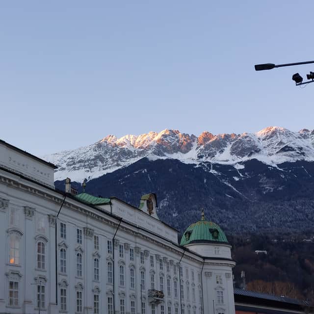 The snow capped peaks above Innsbruck turn golden in the late afternoon as the sun sets.