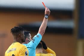 Michael Oliver shows a red card to Arsenal defender Myles Lewis-Skelly.