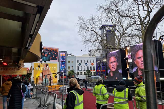 Staff in hi-vis are setting up the red carpet in Leicester Square