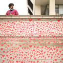 A man wearing medical clothing looks out from above the Covid-19 Memorial Wall outside St Thomas' Hospital in London