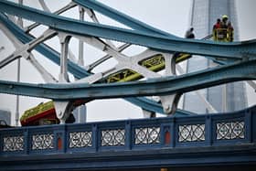Members of the emergency services work to bring down a person who had scaled part of Tower Bridge 