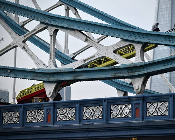 Members of the emergency services work to bring down a person who had scaled part of Tower Bridge 