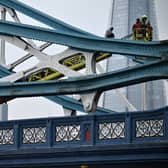 Members of the emergency services work to bring down a person who had scaled part of Tower Bridge 