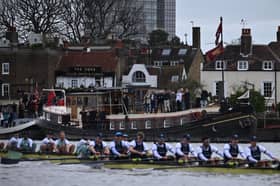 Spectators outside The Dove public House watch during the 168th annual men's boat race between Oxford University and Cambridge University on the River Thames in London