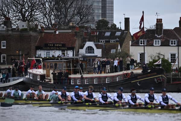 Spectators outside The Dove public House watch during the 168th annual men's boat race between Oxford University and Cambridge University on the River Thames in London