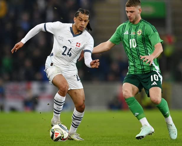 Isaac Schmidt of Switzerland runs with the ball whilst under pressure from Jamie Donley of Northern Ireland during the International Friendly match between Northern Ireland and Switzerland at National Football Stadium, Windsor Park, on March 21, 2025 in Belfast, Northern Ireland. 