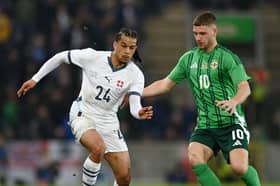 Isaac Schmidt of Switzerland runs with the ball whilst under pressure from Jamie Donley of Northern Ireland during the International Friendly match between Northern Ireland and Switzerland at National Football Stadium, Windsor Park, on March 21, 2025 in Belfast, Northern Ireland. 