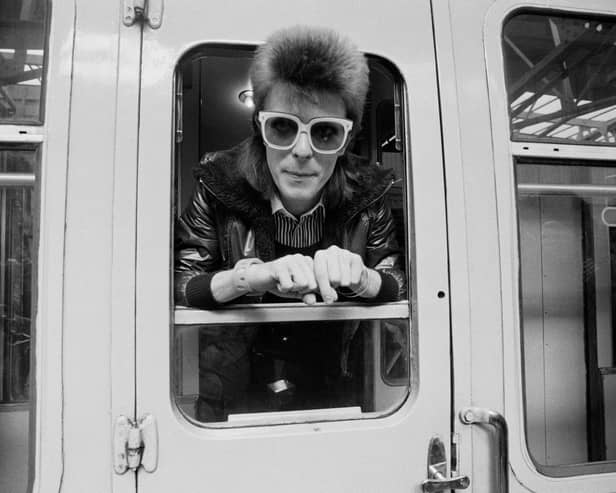 Pop musician David Bowie leaning out of a train window at London Victoria railway station. 