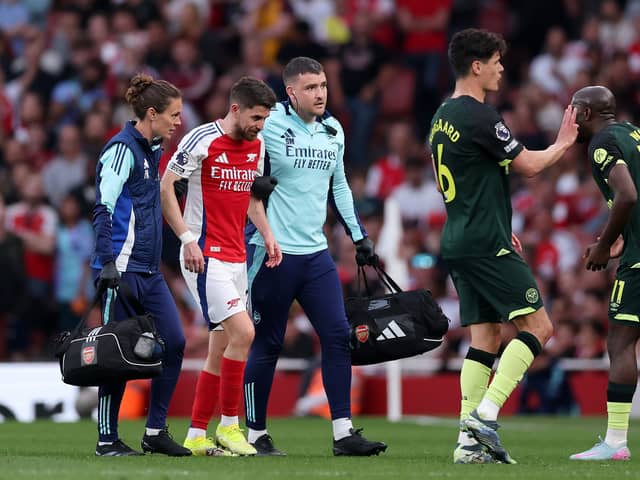 Jorginho of Arsenal is assisted off the pitch by Simon Murphy, Physio of Arsenal, after going down with an injury during the Premier League match between Arsenal FC and Brentford FC at Emirates Stadium on April 12, 2025 in London, England.