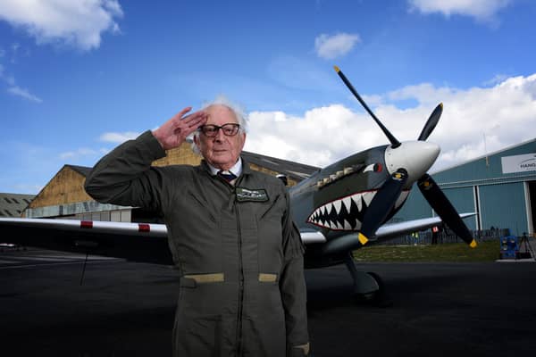 Alan Taylor standing in front of a Spitfire aircraft while saluting