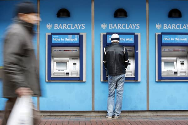 A man uses a cashpoint machine at a Barclays Bank 
