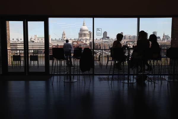 Members of the public sit in a cafe on an upper floor of the Tate Modern gallery overlooking the River Thames and St Paul's Cathedral 