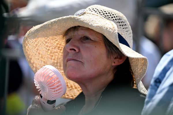 A spectator cools off with a hand held fan on day one of The Championships Wimbledon 2025