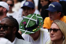 A spectator wearing a hat representing Wimbledon's tennis court with balls, a butterfly and strawberries attends the men's singles fourth round tennis match between Serbia's Novak Djokovic and Australia's Alex De Minaur on the eighth day of the 2025 Wimbledon Championships