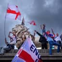 Protesters wave Union Jack and St George's England flags during the "Unite The Kingdom" rally on Westminster Bridge by the Houses of Parliament on September 13, 2025 in London
