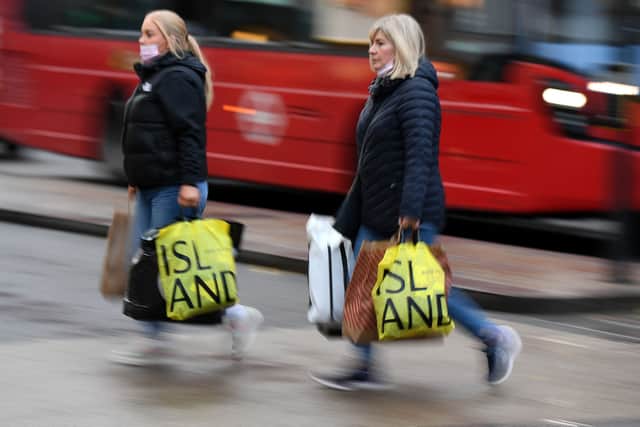 Shoppers carry their purchases from a River Island clothes shop. The retailer has confirmed plans to close 33 UK stores before the end of January 2026 (Photo: DANIEL LEAL/AFP via Getty Images)