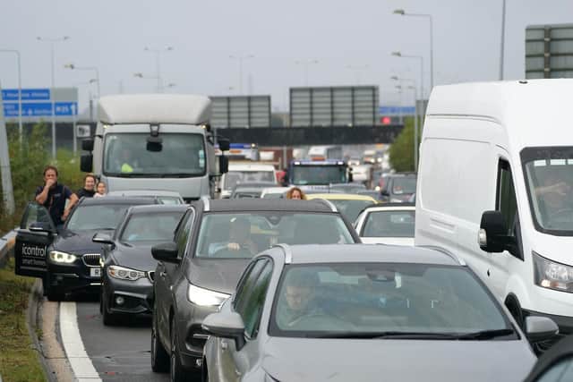 Drivers stand watching from their cars as traffic is halted during a roadblock by protesters from Insulate Britain at a roundabout leading from the M25 motorway to Heathrow Airport in London. Picture date: Monday September 27, 2021. PA Photo. See PA story POLICE Insulate. Photo credit should read: Steve Parsons/PA Wire