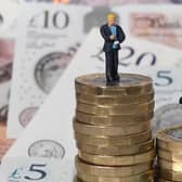 Models of a man and woman stand on a pile of coins and bank notes.