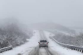 Car drives along snowy road.