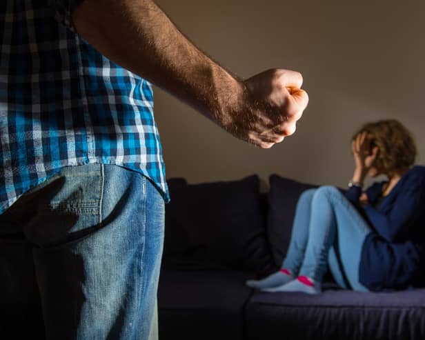 PICTURE POSED BY MODEL A man stands with a clenched fist as a woman cowers in the corner.