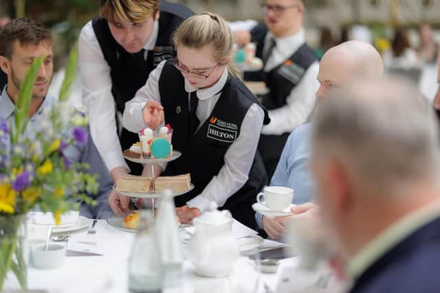 An Aurora Foxes student serves afternoon tea at The Waldorf Hotel