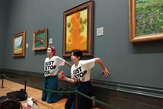 Activists with their hands glued to the wall under Vincent van Gogh's Sunflowers after throwing tomato soup on the painting at the National Gallery in central London. Picture: Just Stop Oil /AFP