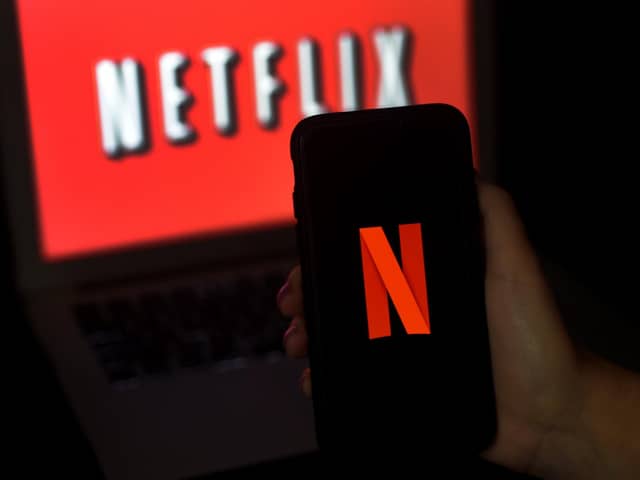 A computer screen and mobile phone display the Netflix logo. Photo by OLIVIER DOULIERY/AFP via Getty Images.