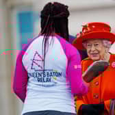 Queen Elizabeth II passes her baton to the baton bearer, British parasport athlete Kadeena Cox. (Photo by Victoria Jones - WPA Pool/Getty Images)