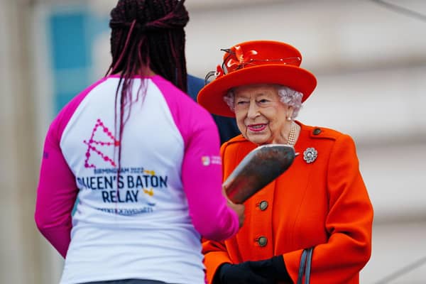 Queen Elizabeth II passes her baton to the baton bearer, British parasport athlete Kadeena Cox. (Photo by Victoria Jones - WPA Pool/Getty Images)