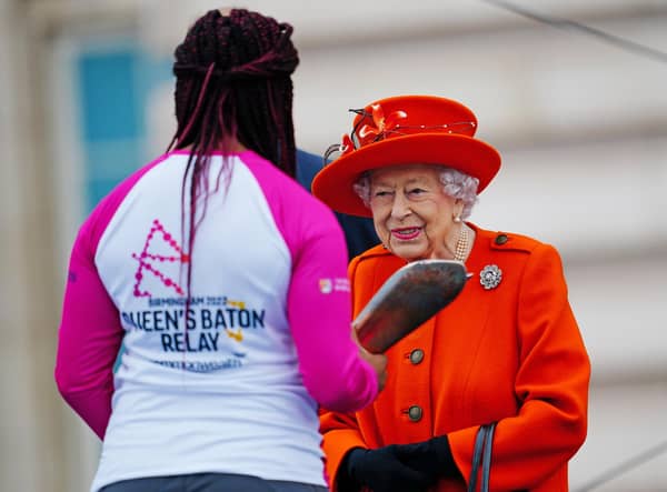 Queen Elizabeth II passes her baton to the baton bearer, British parasport athlete Kadeena Cox. (Photo by Victoria Jones - WPA Pool/Getty Images)