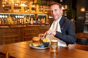 Royal butler eating a burger with a knife and fork