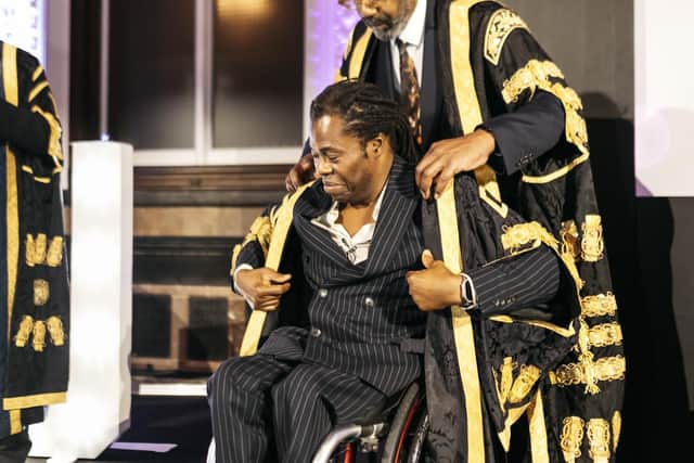 Sir Lenny Henry helps Ade Adepitan don his ceremonial robes for the first time