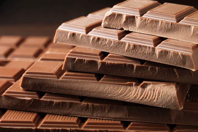 Multiple chocolate bars are laying on top of one another against a black background.