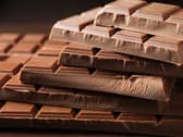 Multiple chocolate bars are laying on top of one another against a black background.