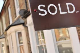 An estate agent's "sold" board stands outside a residential building.