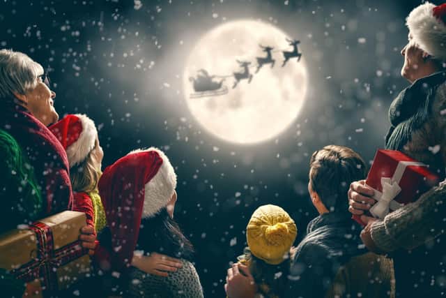 People looking up at the night sky at Santa on his sleigh.