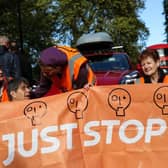 Members of the environmental activist group Just Stop Oil hold a banner as they block Park Lane, in central London, on Sunday 