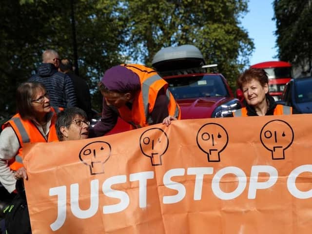 Members of the environmental activist group Just Stop Oil hold a banner as they block Park Lane, in central London, on Sunday 