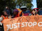 Members of the environmental activist group Just Stop Oil hold a banner as they block Park Lane, in central London, on Sunday 