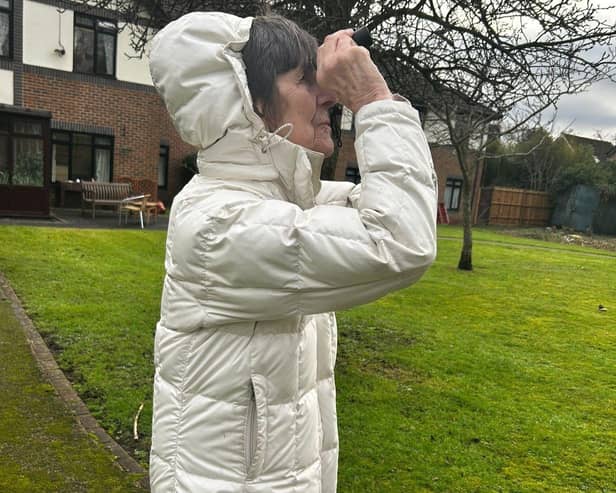 Resident Elaine Pieter looking at parakites through binoculars