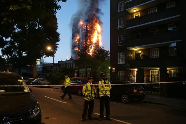 In this file photo taken on June 14, 2017 police man a security cordon as a huge fire engulfs the Grenfell Tower early June 14, 2017 in west London. Photo by Daniel Leal-Olivas / AFP via Getty Images.